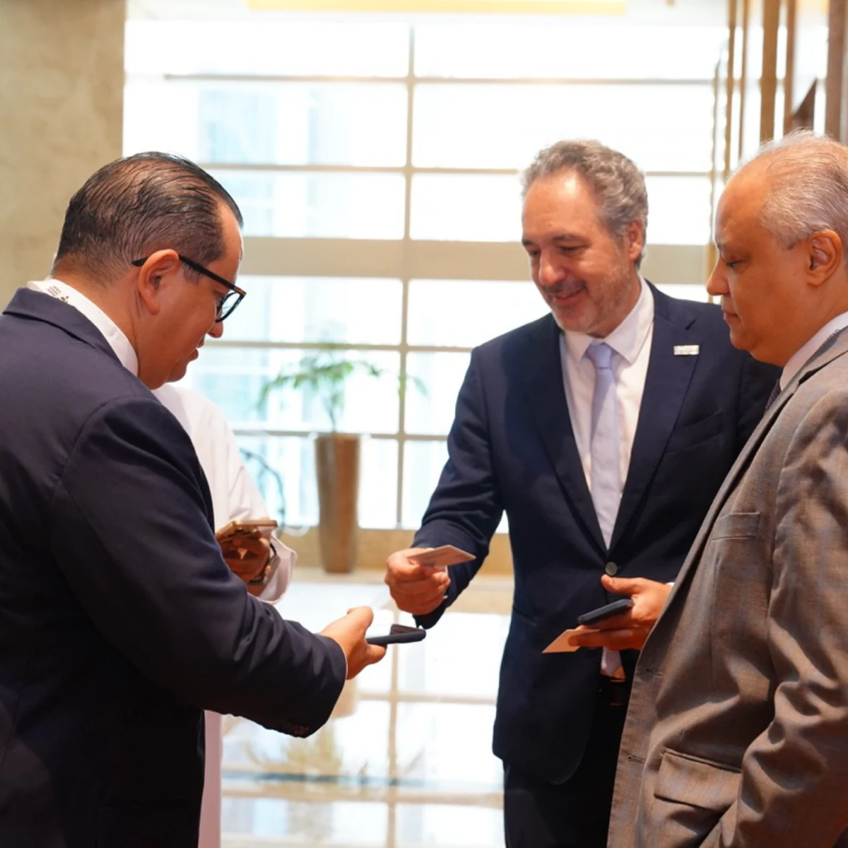 Three delegates exchanging business cards between sessions at a previous Islamic Fintech Forum